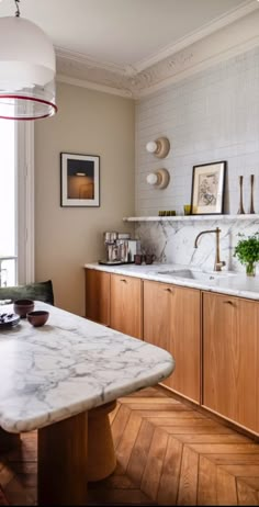 a kitchen with marble counter tops and wooden cabinets, along with pictures on the wall