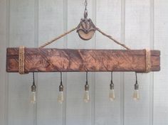 a wooden beam hanging from a rope with light bulbs attached to the end and two lights on each side