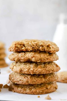 three oatmeal cookies stacked on top of each other next to a glass of milk