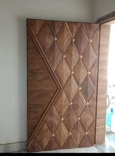 a large wooden door in the corner of a room with white walls and tile flooring