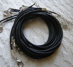 a close up of a black leather cord on a white table cloth with silver chains