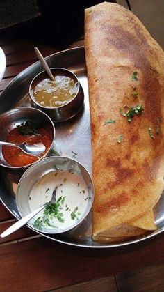 a large pita on a silver plate with sauces and condiments