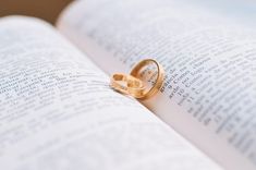 two gold wedding rings resting on an open book