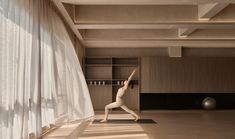 a woman is doing yoga in the middle of an empty room with curtains on both sides