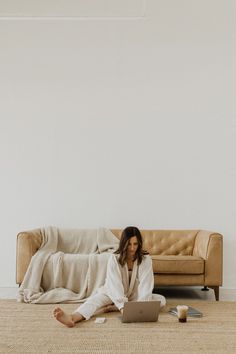 a woman sitting on the floor with her laptop