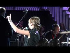 a woman with her hand up in the air while singing into a microphone on stage