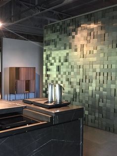 an empty room with black counter tops and green tiles on the wall behind it,