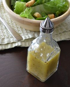 a salad with dressing in a glass bottle next to a bowl of lettuce