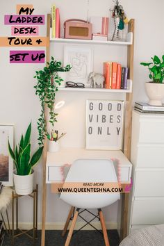 a white desk with some plants and pictures on the wall next to it in front of a bookshelf