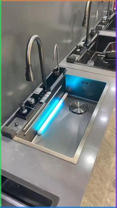 a stainless steel kitchen sink with blue light under the faucet and countertop