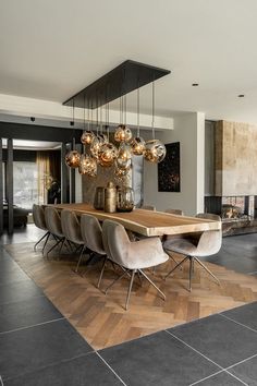 a dining room table with chairs and lights hanging from it's centerpieces