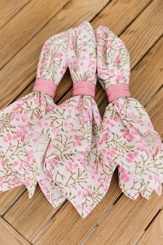 three pink and white flowered ties on a wooden surface