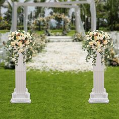 two white vases with flowers on them in front of an outdoor wedding ceremony setup