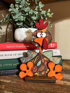 a wooden turkey sitting on top of a stack of books