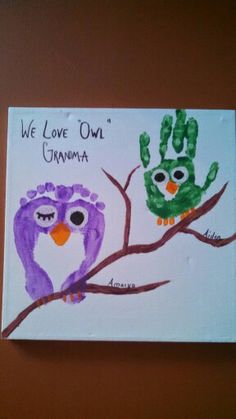 two owls are sitting on a tree branch painted with handprints