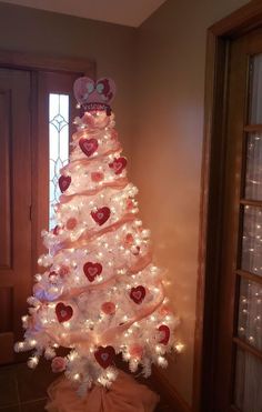 a white christmas tree decorated with hearts and bows