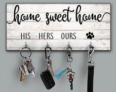 a sign that says home sweet home with keys hanging from it's hooks and keychains