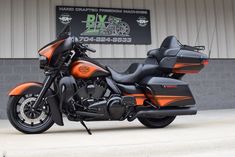 an orange and black motorcycle parked in front of a building