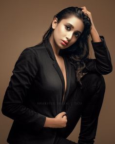 a woman in black is posing for the camera with her hands on her head and one hand on her hair