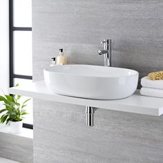 a white sink sitting on top of a counter next to a potted green plant