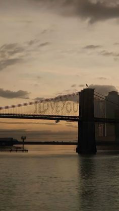 an image of a bridge that is going over the water at sunset or dawn with clouds in the sky