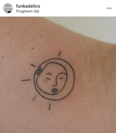 a tattoo on the back of a woman's shoulder that has a drawing of a sun and a sleeping face