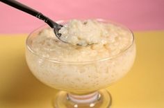 a spoon full of rice in a small glass bowl on a yellow and pink background