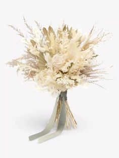 a bouquet of dried flowers in a vase on a white tablecloth with ribbon tied around it