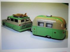 two green and beige toy buses on a white surface with one car parked next to the other