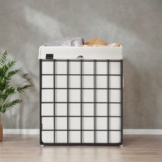 a white and black storage box next to a potted plant