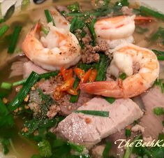 a white bowl filled with soup and shrimp on top of green beans, carrots and broccoli