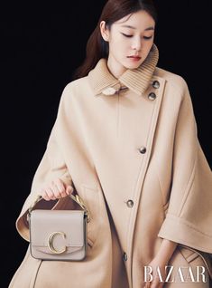 a woman in a beige coat carrying a gray bag