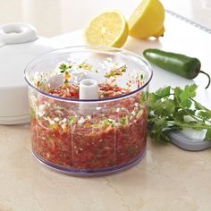 a food processor filled with meat and vegetables on top of a counter next to lemons