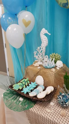 a table topped with cookies and balloons on top of a table covered in blue and white decorations