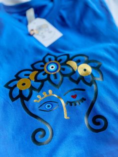 a blue t - shirt with an image of a woman's face painted on it