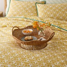 a wicker tray with food on top of it sitting on a bed in a bedroom