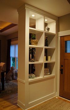 a white book shelf sitting on top of a hard wood floor next to a door