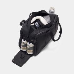 an open black duffel bag with baby bottles and diapers in it on a white background