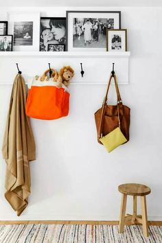 two purses hanging from hooks on a wall with pictures and photos above them in the background