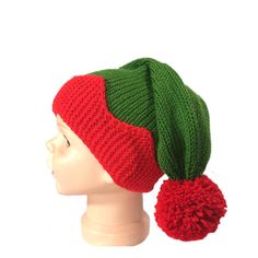 a red and green knitted hat with pom - poms on top of a mannequin head