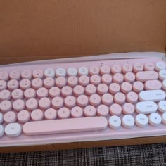 a pink computer keyboard sitting in a cardboard box