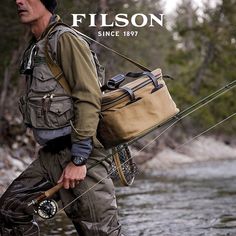 a man standing in the water holding a fishing rod and a bag on his back