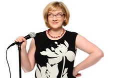 a woman holding a microphone in her right hand and wearing a black shirt with white flowers on it