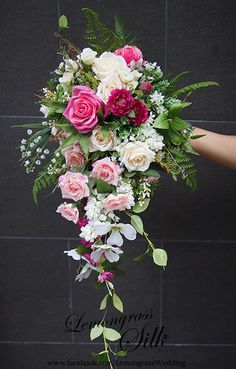 a bridal bouquet with pink and white flowers on display in front of a brick wall