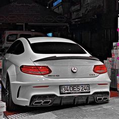 the back end of a white car parked in a garage