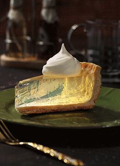 a piece of pie with whipped cream on top sitting on a plate next to a fork