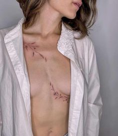 a woman with tattoos on her chest wearing a white shirt