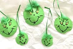 four green ornaments with faces drawn on them