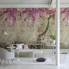 a living room with pink flowers on the wall and white furniture in front of it