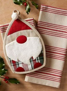 two christmas towels with santa claus face on them and holly leaves in the corner next to it